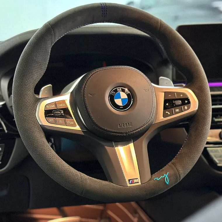 BMW steering wheel with a dark gray Alcantara cover and turquoise custom initials embroidery